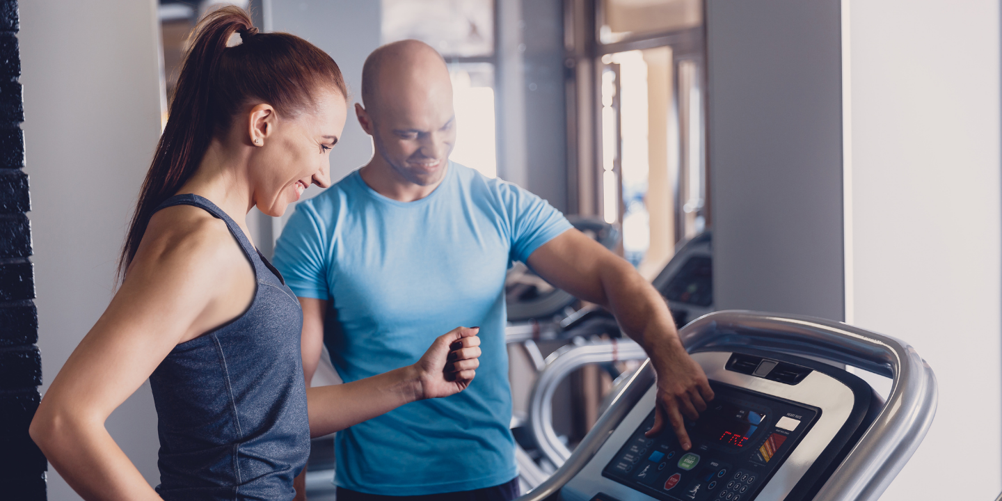 woman walking on a treadmill while a coach performs walking gait analysis